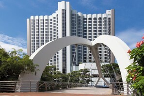 Un bâtiment moderne doté d’une entrée arquée originale et d’une haute structure résidentielle en arrière-plan.