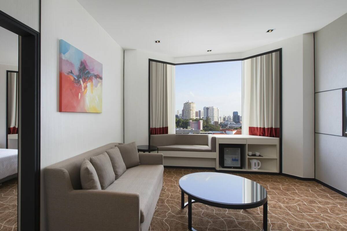 Une chambre d’hôtel avec un lit, un canapé, une table basse et une vue sur les toits de la ville.