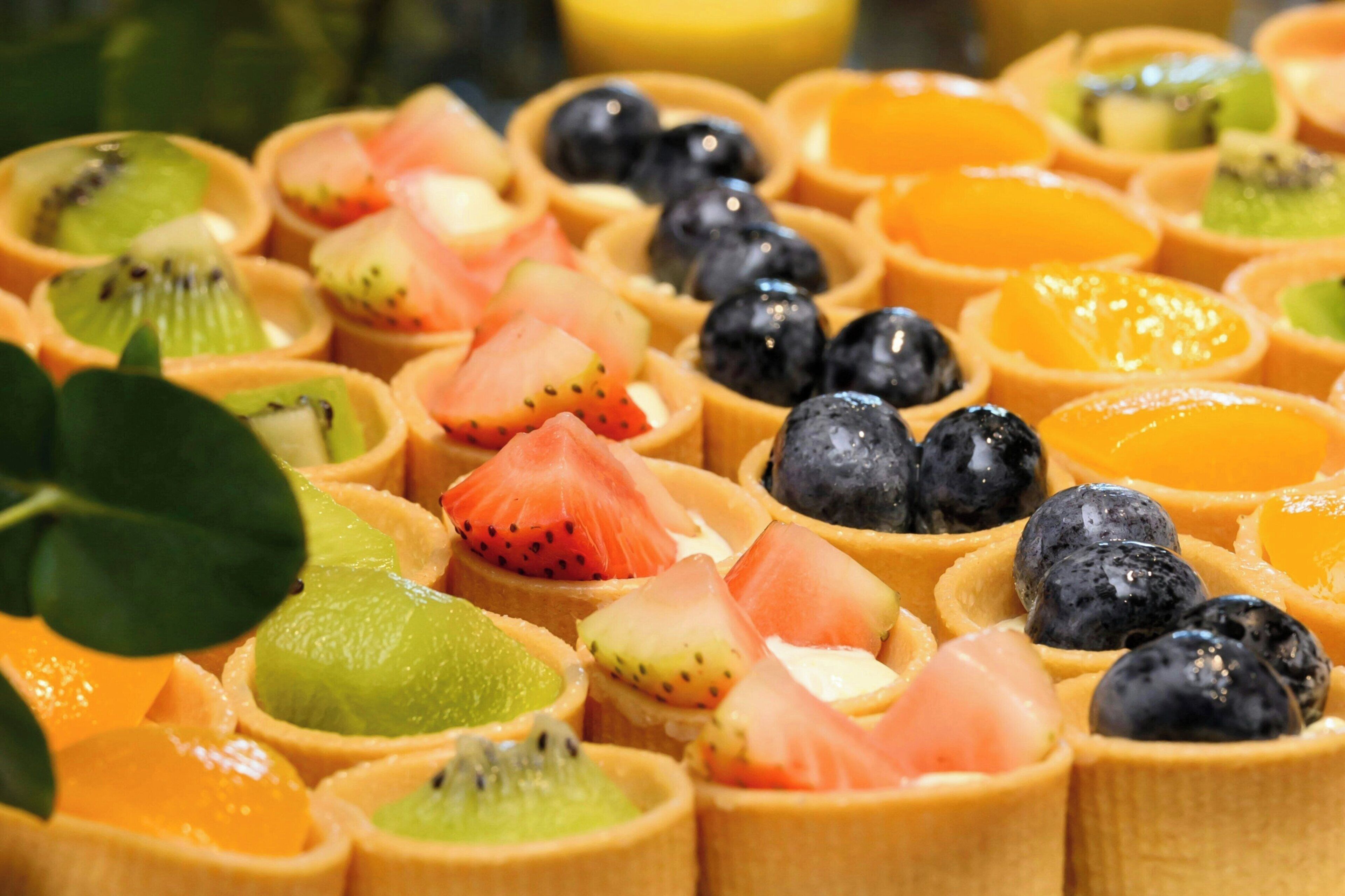 A variety of fruit tarts in individual cups.