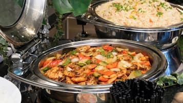 Un bufé con diversos platos, incluyendo verduras salteadas y arroz.