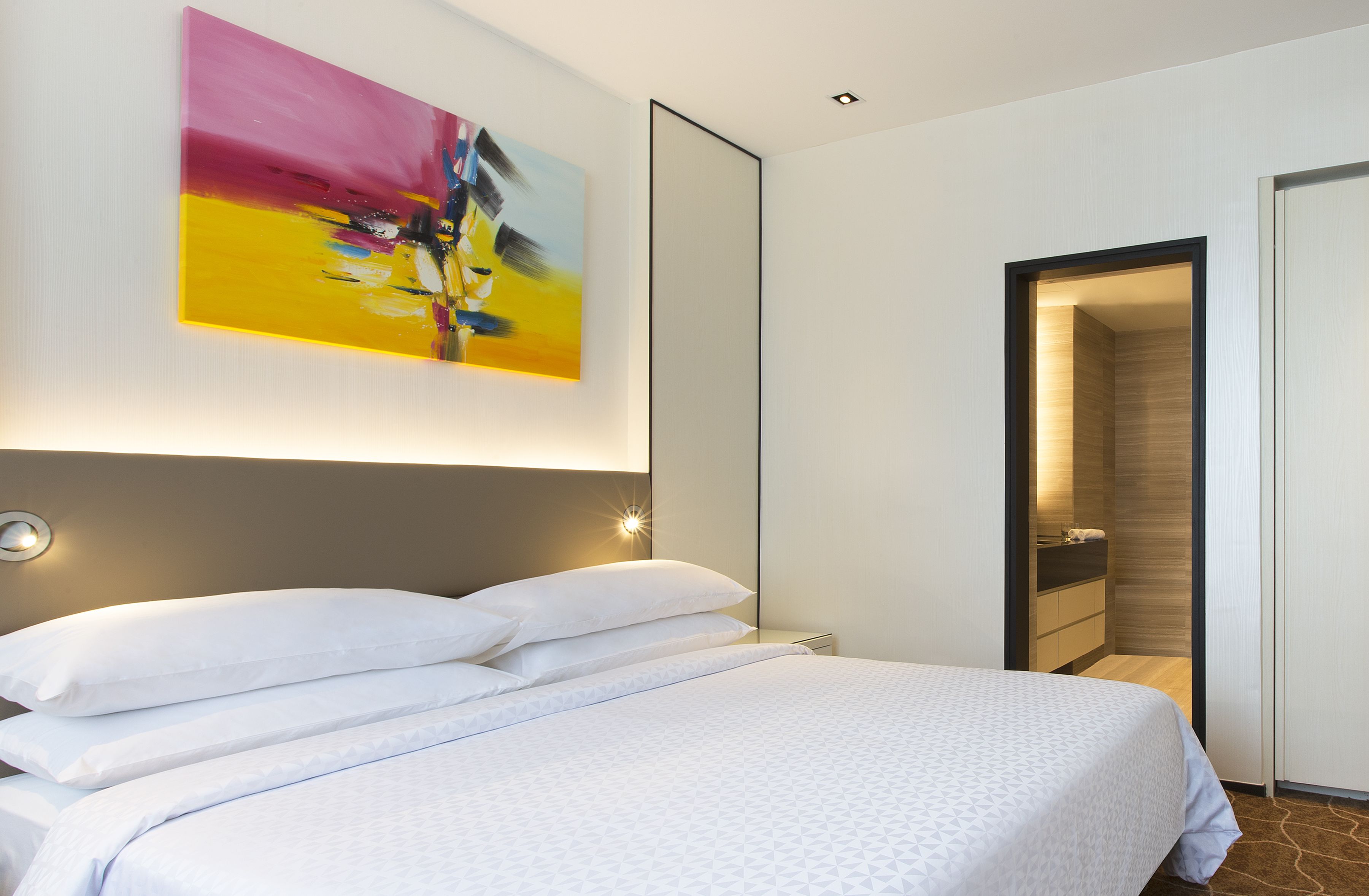 Una habitación de hotel moderna con una cama grande, un cuadro en la pared y un vestidor.