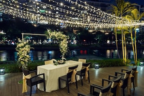 Enjoy al fresco dining by the water with a table set for six surrounded by comfortable chairs.