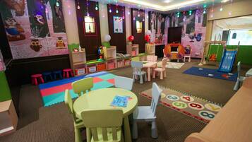 A children's play area with tables, chairs, and colorful play mats.