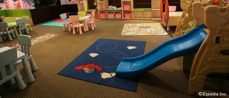 A children's play area with a blue slide, play mats, and colorful decorations.