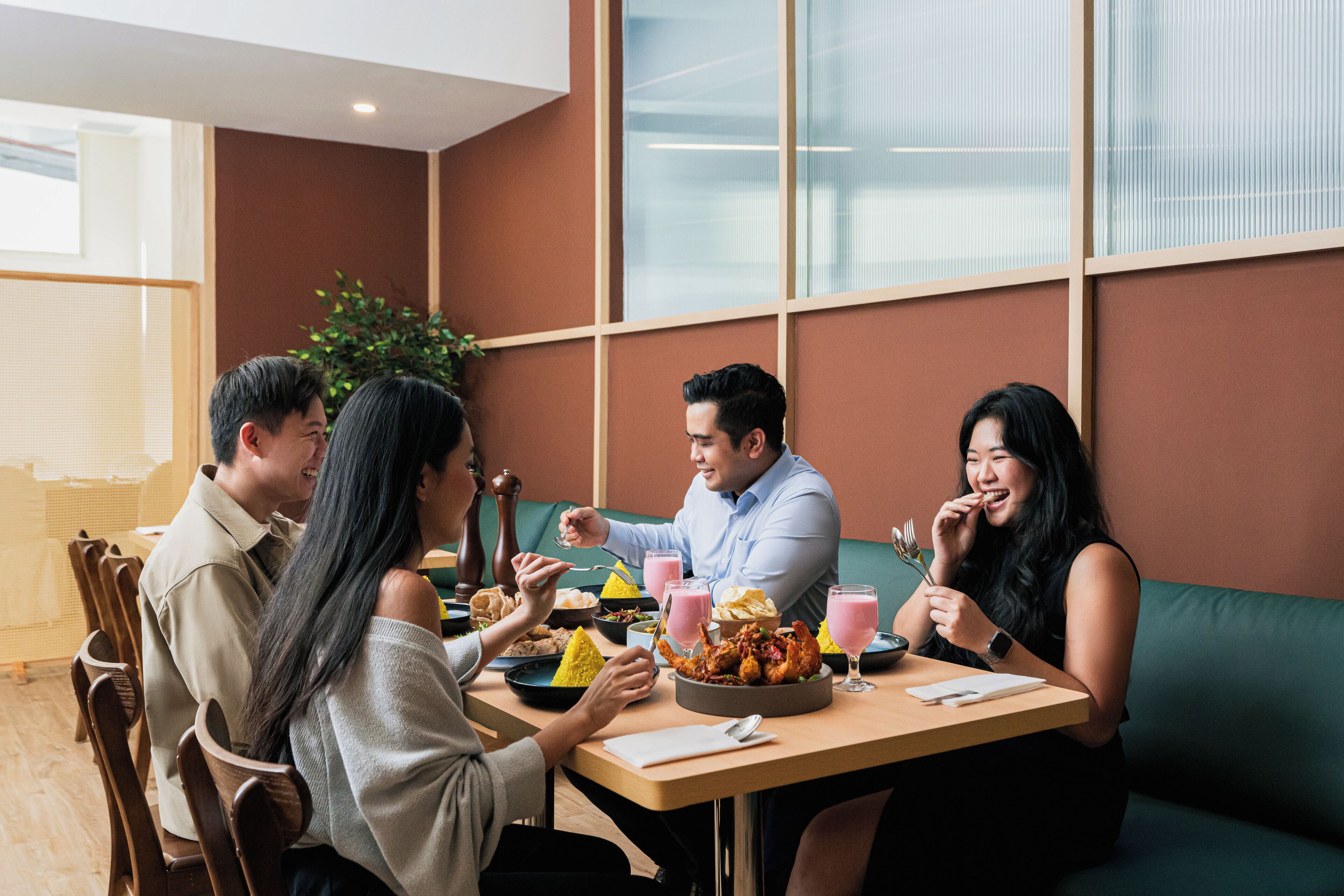 A group of people dining at a restaurant with a wooden table, chairs, and a green couch.