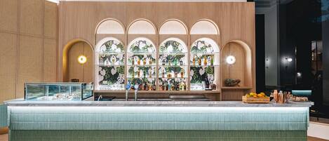 A bar area with a counter, shelves with bottles, and a display case.