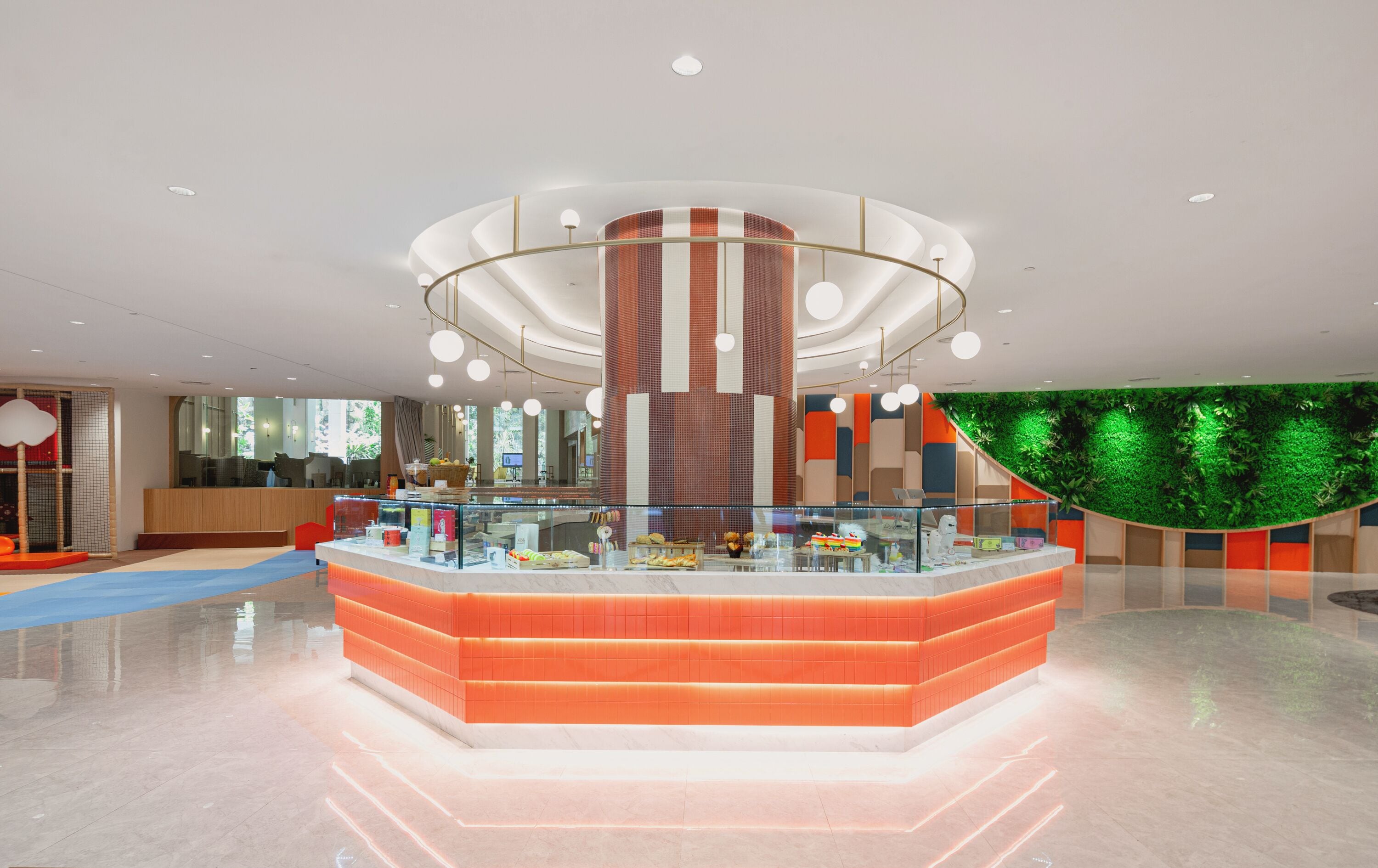 A modern lobby with a central circular counter, a large vertical column, and a green wall with plants.