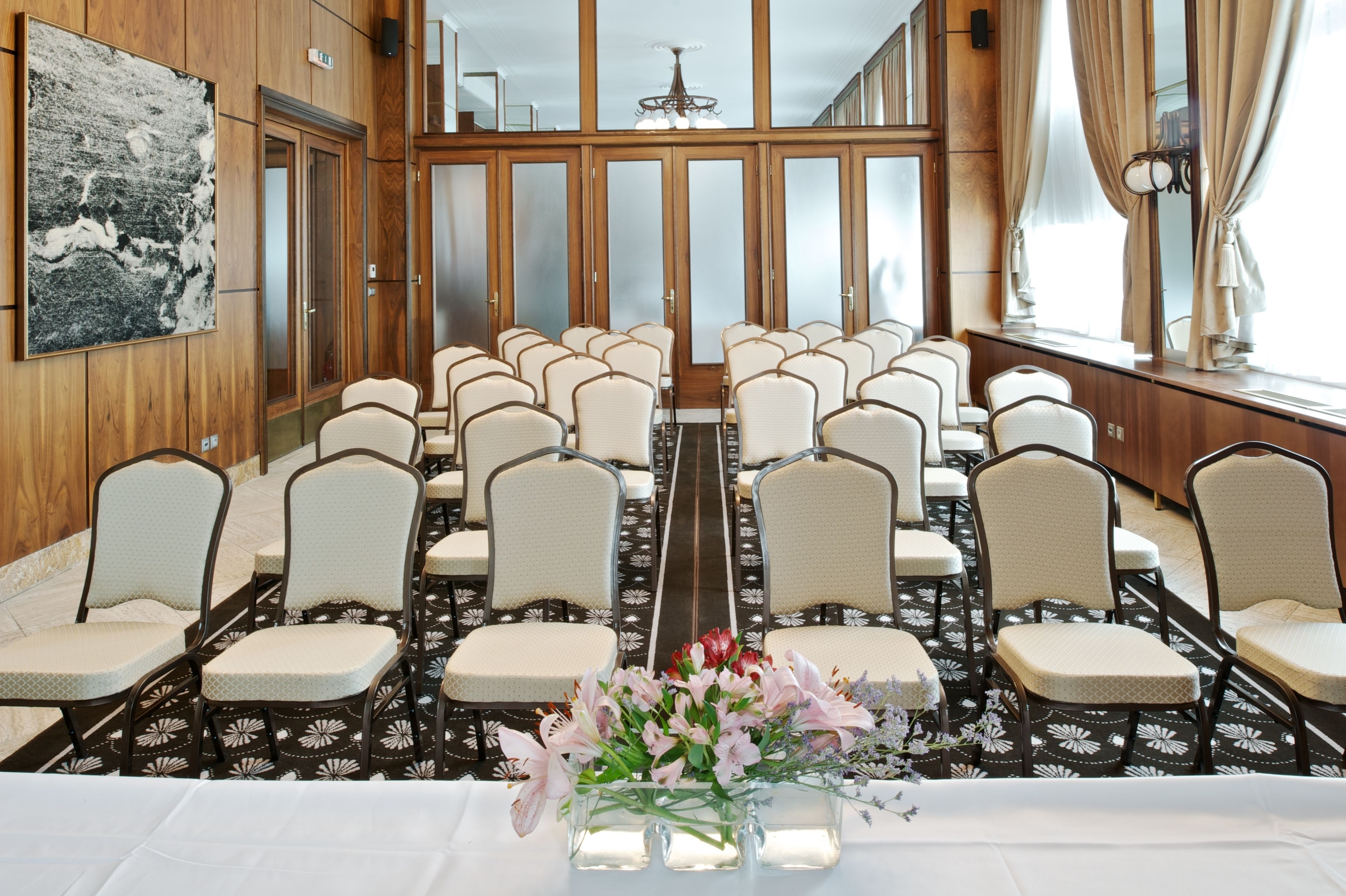 A conference room with rows of chairs, a long table, and a floral centerpiece.