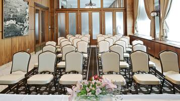 A conference room with rows of chairs, a long table, and a floral centerpiece.
