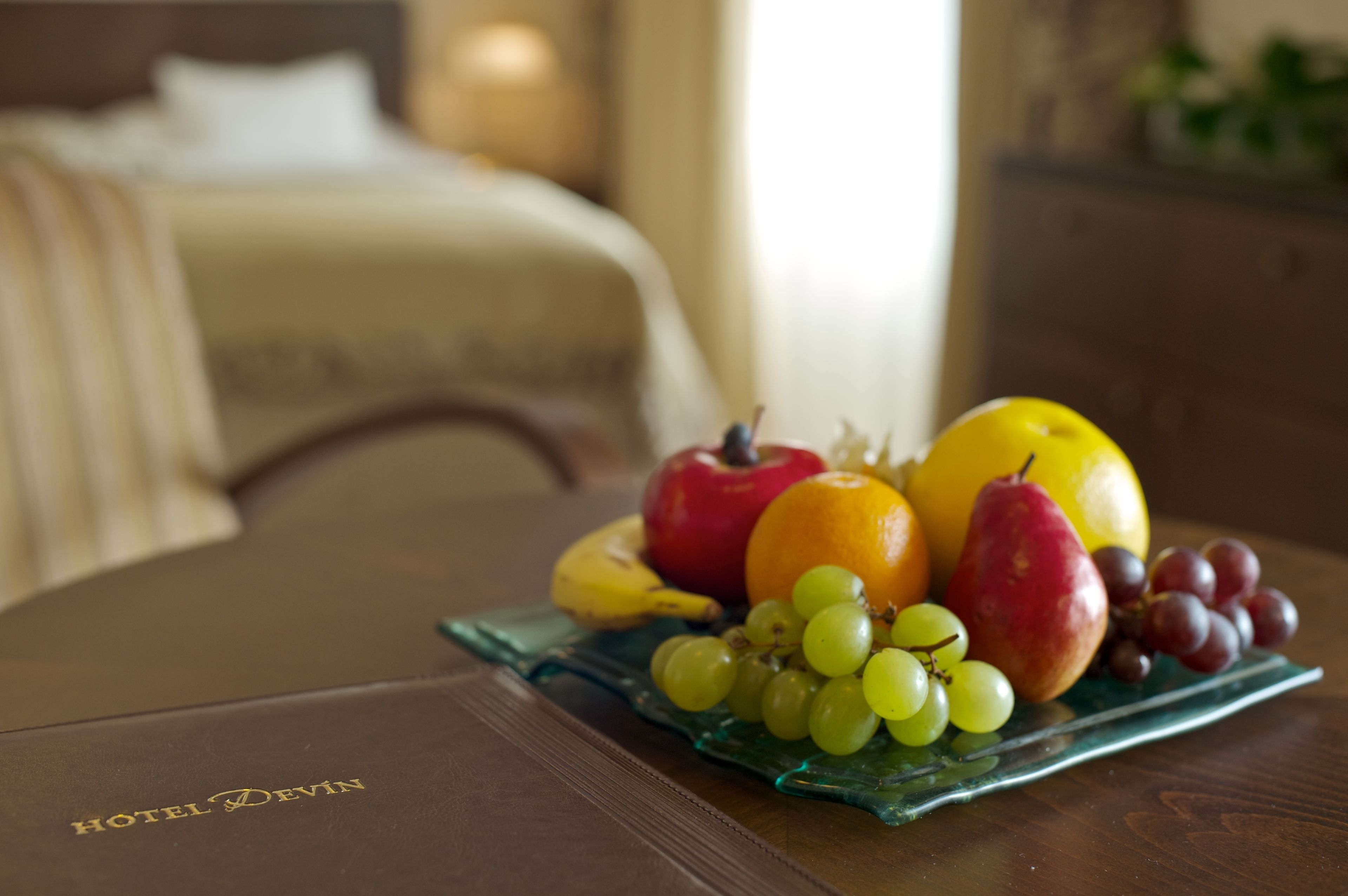 Una bandeja de fruta sobre una mesa con un folleto de hotel.