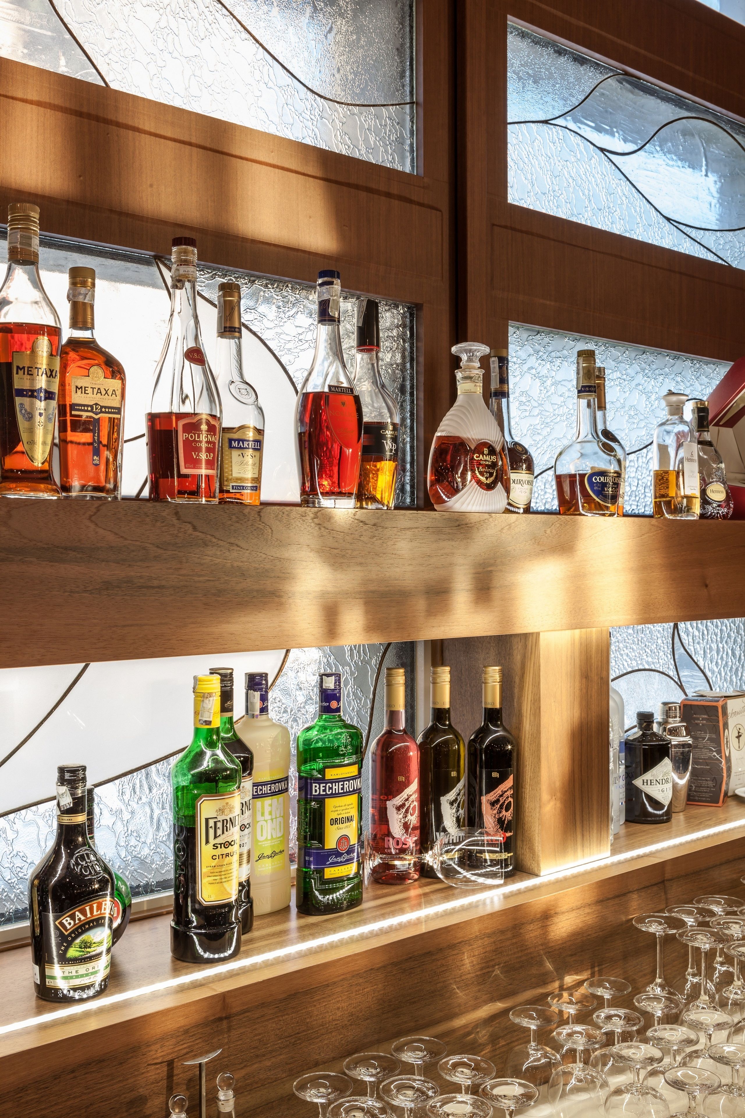 A bar with multiple shelves of liquor bottles and glasses.