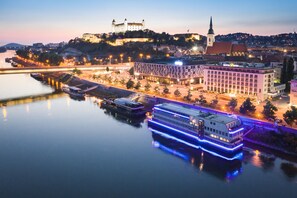 A large hotel with a prominent building and a castle in the background. - Devin Hotel (Bratislava)