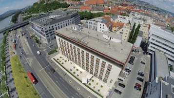 Un hotel con un patio central, rodeado por un estacionamiento y edificios adyacentes.