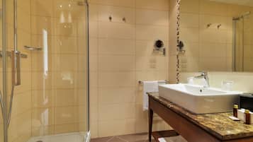 A modern bathroom with a glass-enclosed shower, a large sink with a marble countertop, and a mirror above the sink.
