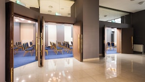 Uma sala de conferências com fileiras de cadeiras, piso lustroso e design de teto moderno.