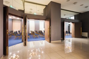 Une salle de conférence avec des rangées de chaises, un plancher ciré et un design de plafond moderne.