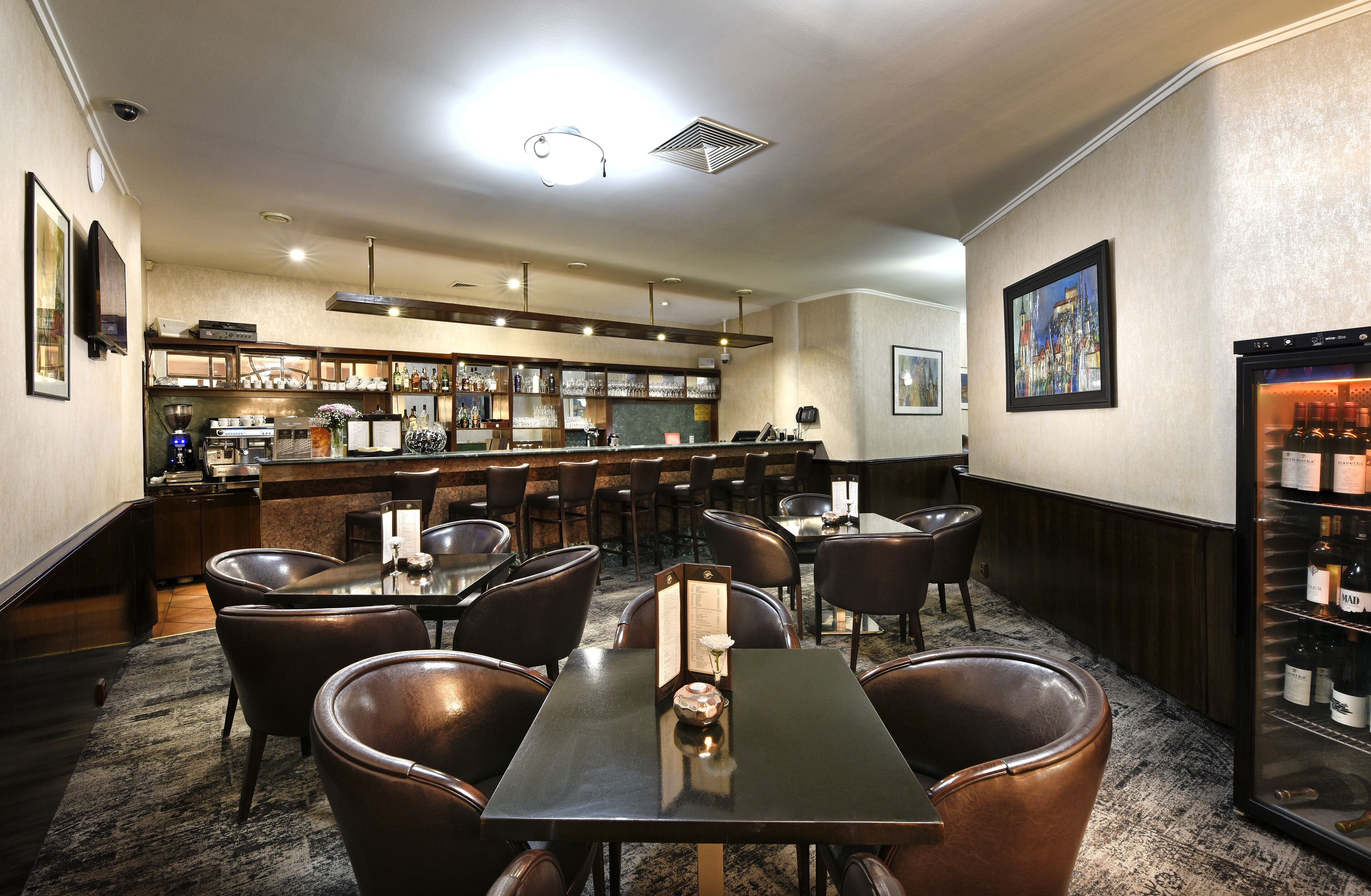 A restaurant with a bar area, multiple tables, and chairs.