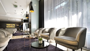 Uma sala de estar moderna com um sofá, uma mesa de centro redonda com uma planta e iluminação pendente.