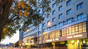 Um hotel com fachada moderna, vários andares e um letreiro grande que diz 'Hotel Parking'.