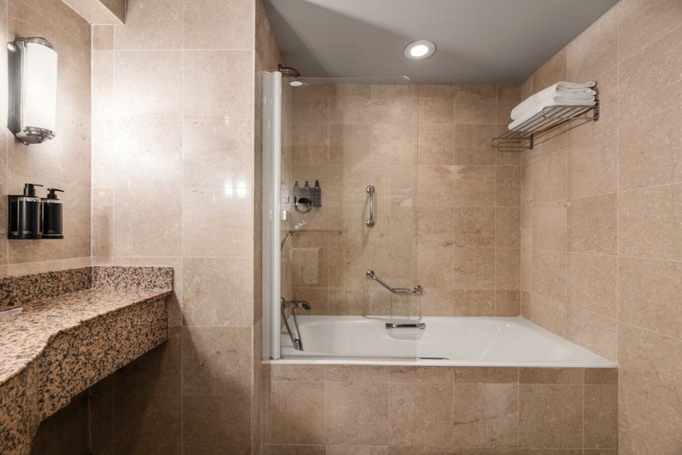 Une salle de bain moderne équipée d’une douche, d’un lavabo intégré et d’un porte-serviettes.