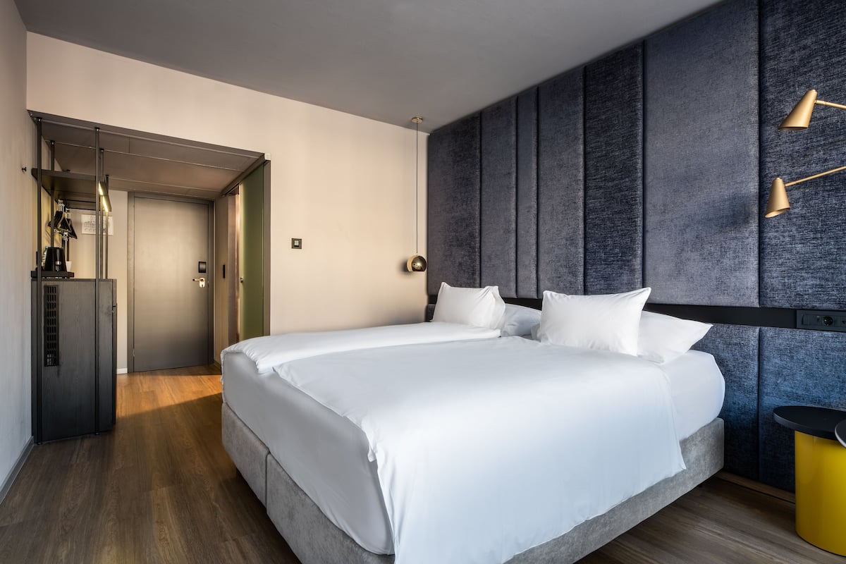 Una habitación de hotel moderna con una cama grande, un armario y un banco empotrado.