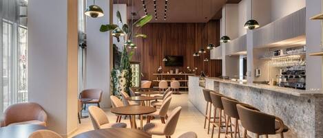 A modern cafe with round tables and bar stools, wooden accents, and a bar area with a coffee machine.