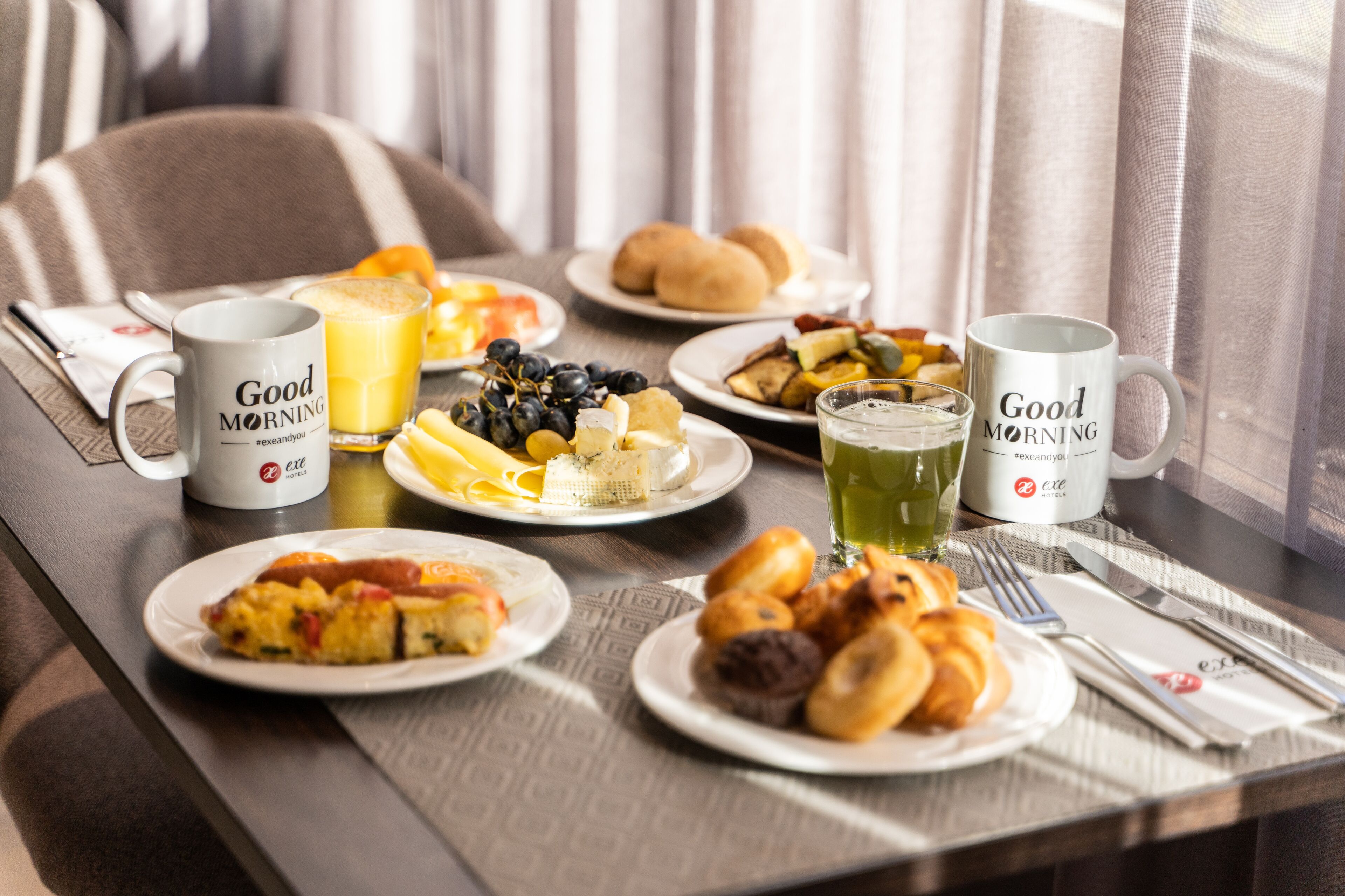 Une table de petit-déjeuner avec des assiettes remplies de nourriture, deux tasses et un verre de jus.