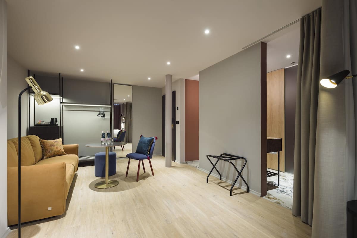 Una sala de estar moderna con un sofá, un sillón, una mesita redonda y una lámpara.