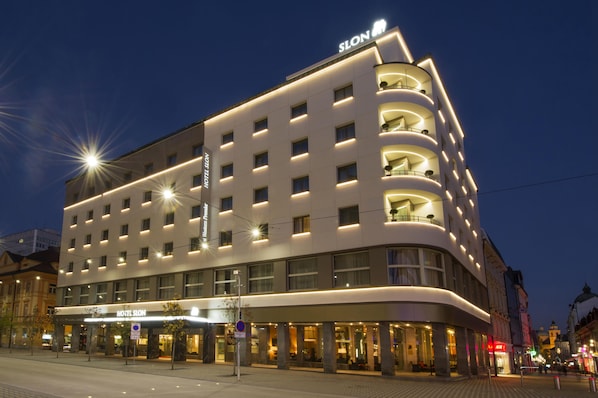 A modern hotel with a prominent 'HOTEL SLON' sign, multiple balconies, and a well-lit facade. - Best Western Premier Hotel Slon (Ljubljana)
