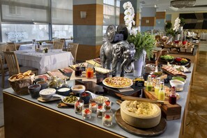 Un buffet proposant une variété de plats, notamment des viandes, des fromages et des desserts, disposés sur un comptoir agrémenté d’une sculpture décorative d’éléphant.