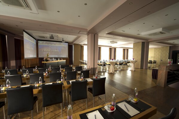 A conference room with multiple tables, chairs, a podium, and a presentation screen. - Best Western Premier Hotel Slon (Ljubljana)