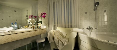 A bathroom with a bathtub, a shower, a vanity with a mirror, and a stool.