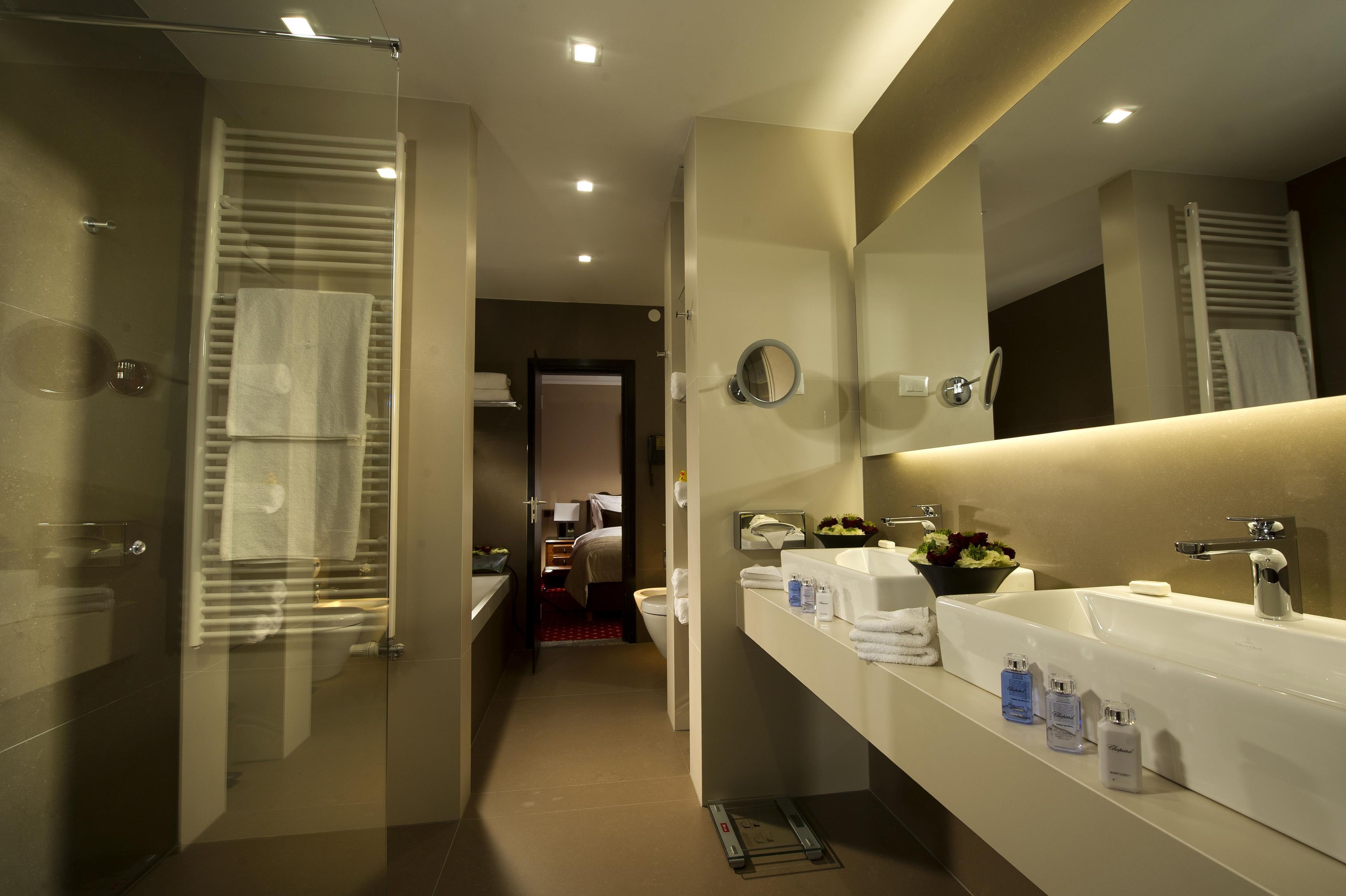 A modern bathroom with a glass shower enclosure, a large mirror, and a vanity with a sink and towel rack.