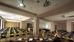 Une salle de conférence avec des rangées de tables et de chaises, équipée de plaques nominatives et de bouteilles d’eau.