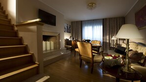 Une chambre d’hôtel avec un escalier, un téléviseur à écran plat fixé au mur, un coin repas avec une table et des chaises, un canapé et une lampe.