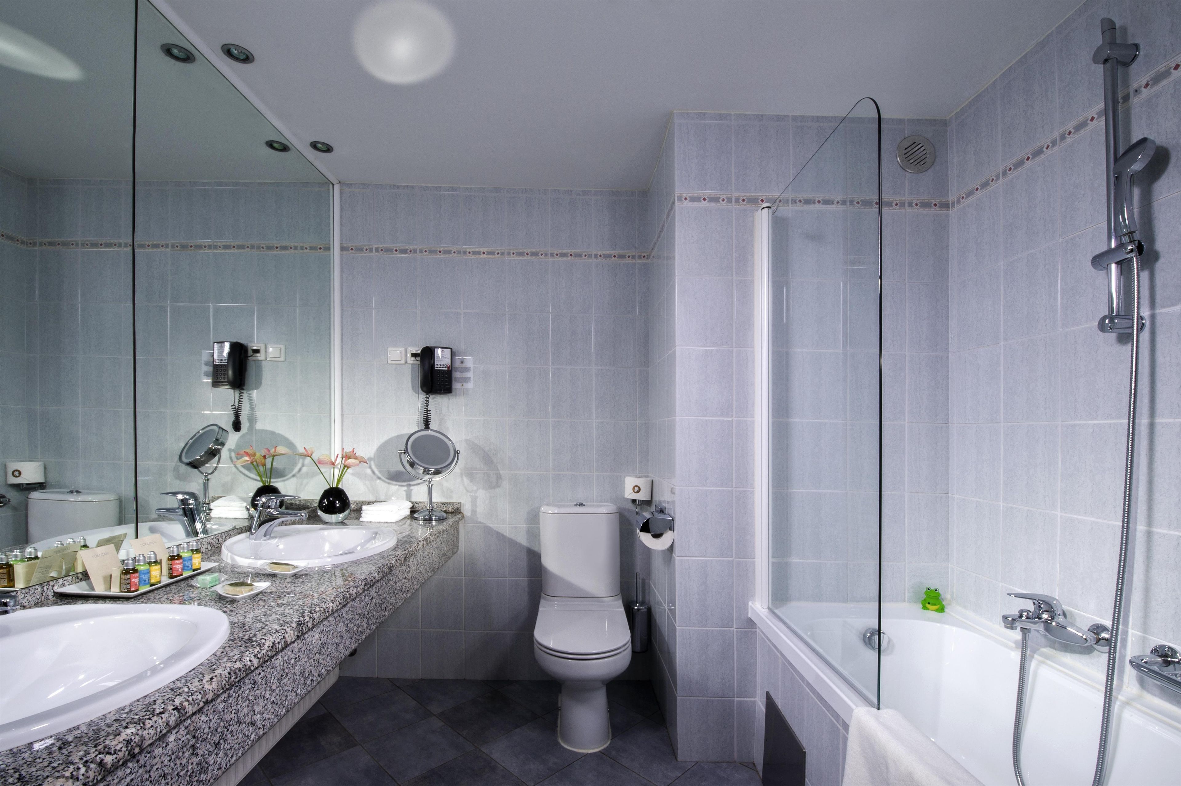 Ein modernes Badezimmer mit einem Doppelwaschtisch, einer Toilette, einer Duschkabine und einem großen Spiegel.