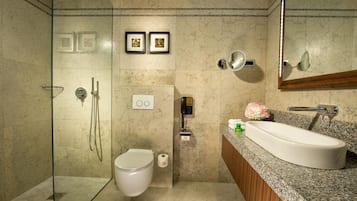 A modern bathroom with a glass-enclosed shower, a toilet, a sink with a granite countertop, and a mirror.