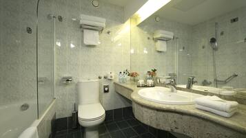 Un baño moderno con inodoro, bidé y lavamanos con espejo.