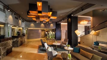 Um lobby moderno com balcão de recepção, área de estar e escada.