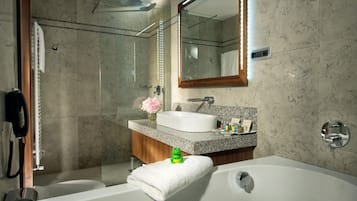 A modern bathroom with a glass-enclosed shower, a white bathtub, a vanity with a sink, and a mirror above the vanity.