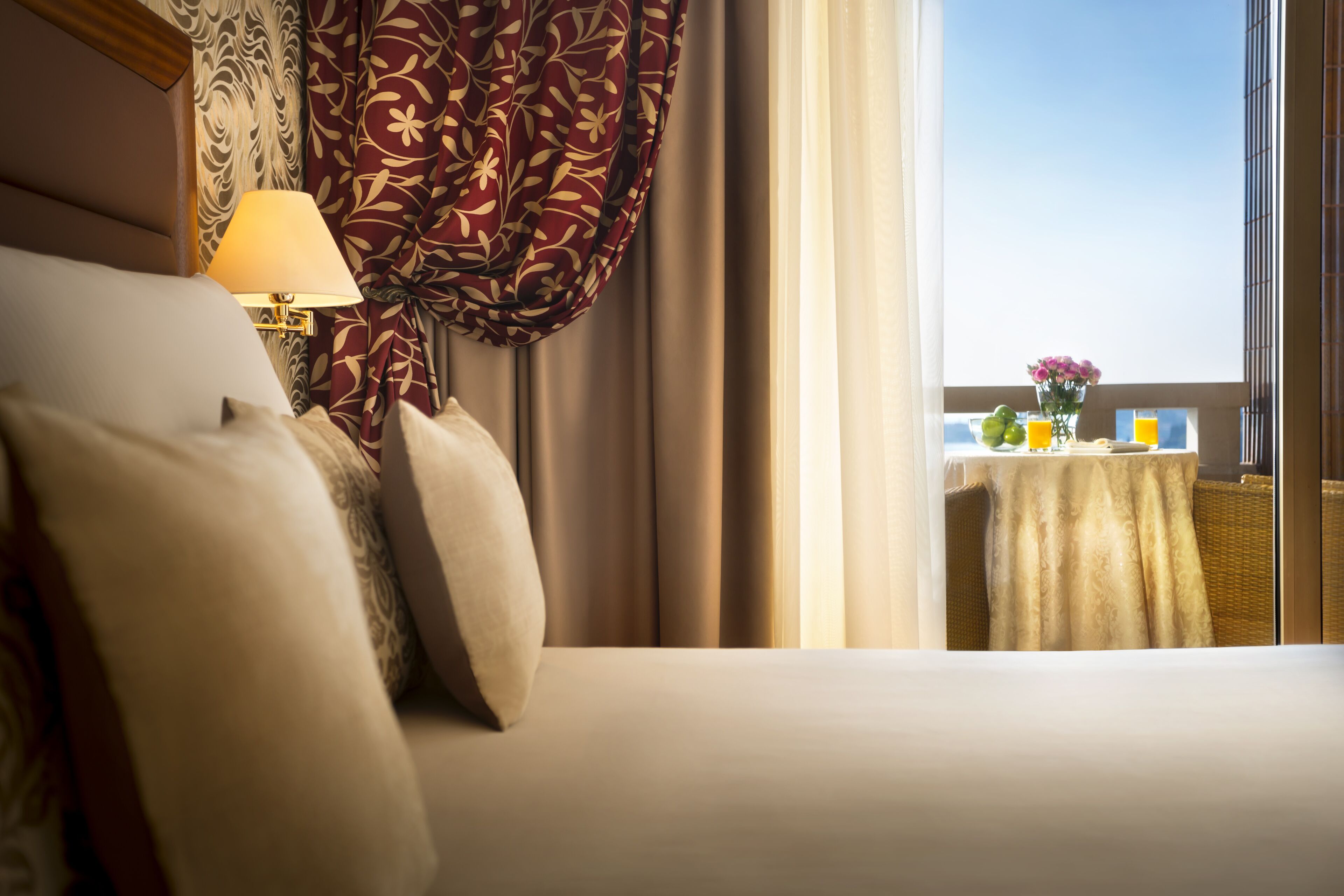 Una habitación de hotel con una cama, una mesa con un florero y vistas al cielo.