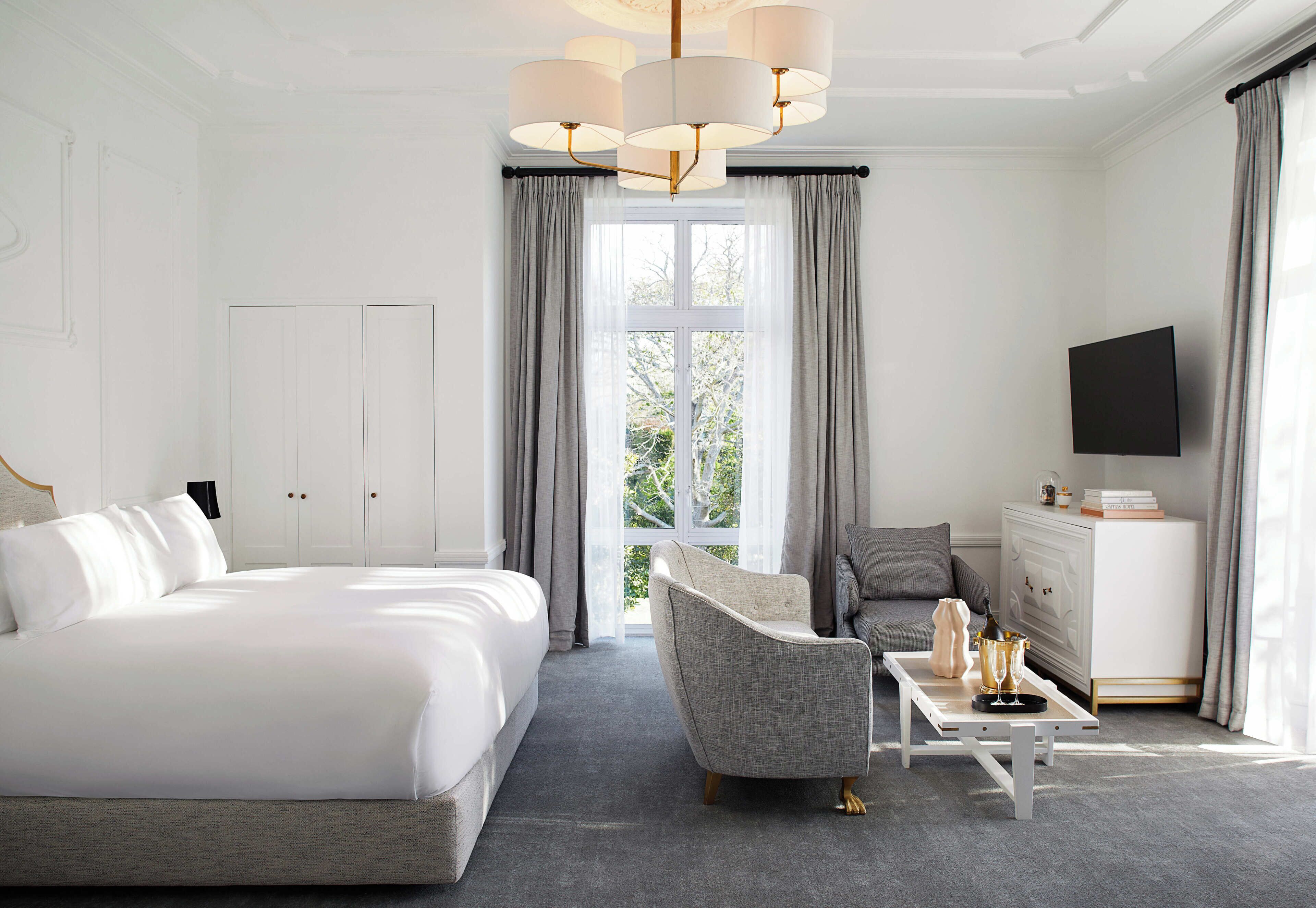 Ett hotellrum med en stor säng, en soffa, ett soffbord och en tv.