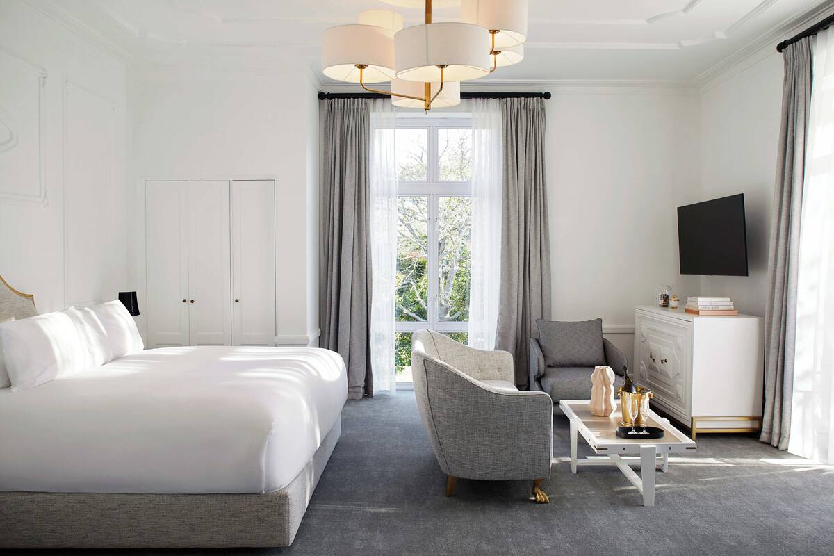 Una habitación de hotel con una cama grande, un sofá, una mesa de centro y un televisor.