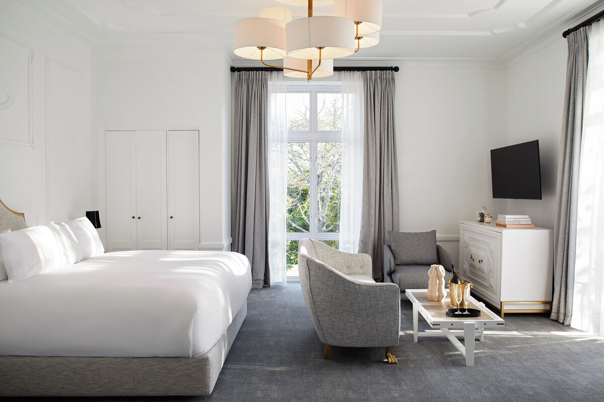 A hotel room with a large bed, a sofa, a coffee table, and a TV.