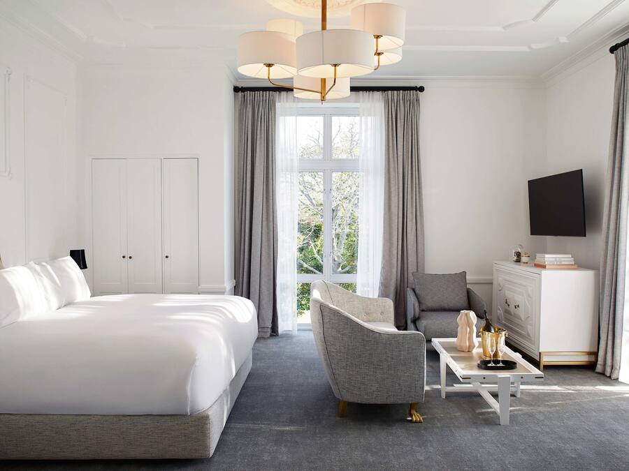 A hotel room with a large bed, a sofa, a coffee table, and a TV.