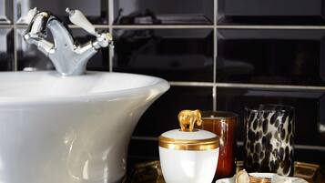 Un baño con un lavabo blanco, grifos dorados y encimera de mármol.