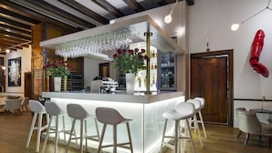 A modern bar area with a white bar counter, multiple stools, and a wine rack. - The Alphen Boutique Hotel & Spa (Cape Town)