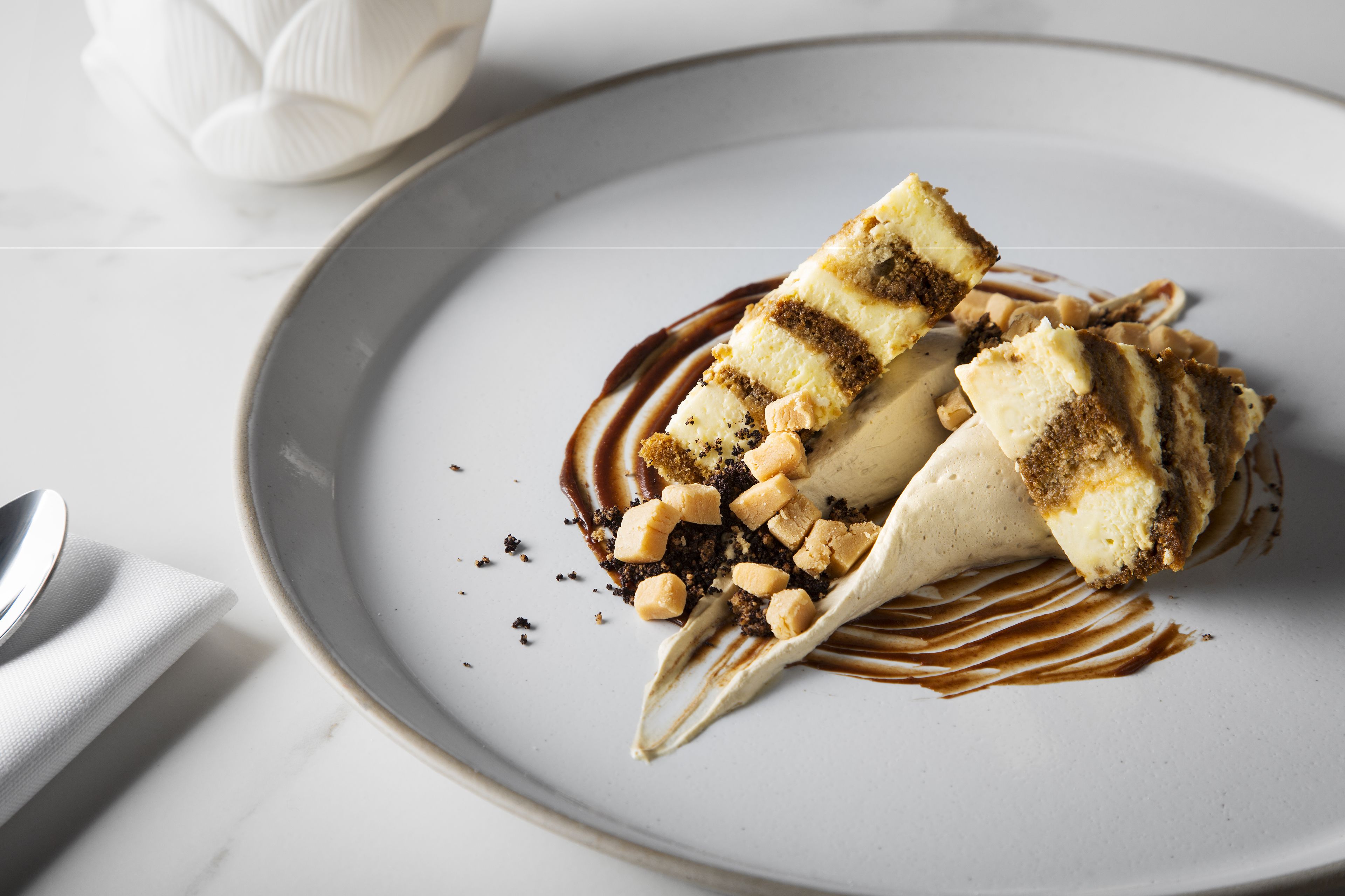 Ein Dessert auf einem Teller mit Schokoladensauce und Nüssen.