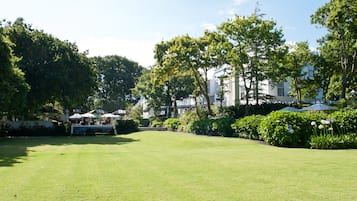 A well-maintained lawn with a gazebo and a white building in the background.