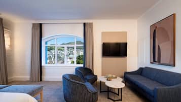 Habitación de hotel con un ventanal grande que ofrece vistas a la ciudad, un sofá, una silla, una mesita y una cama.